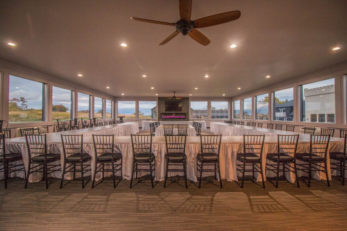 The conference room set up with long draped tables, windows on three sides and a fireplace at the far end