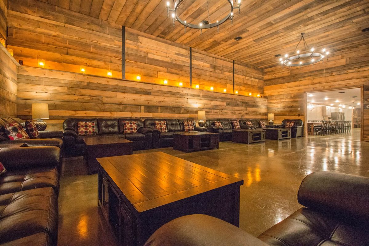 The living room: a long timber-clad hall lined with leather sofas under iron chandeliers