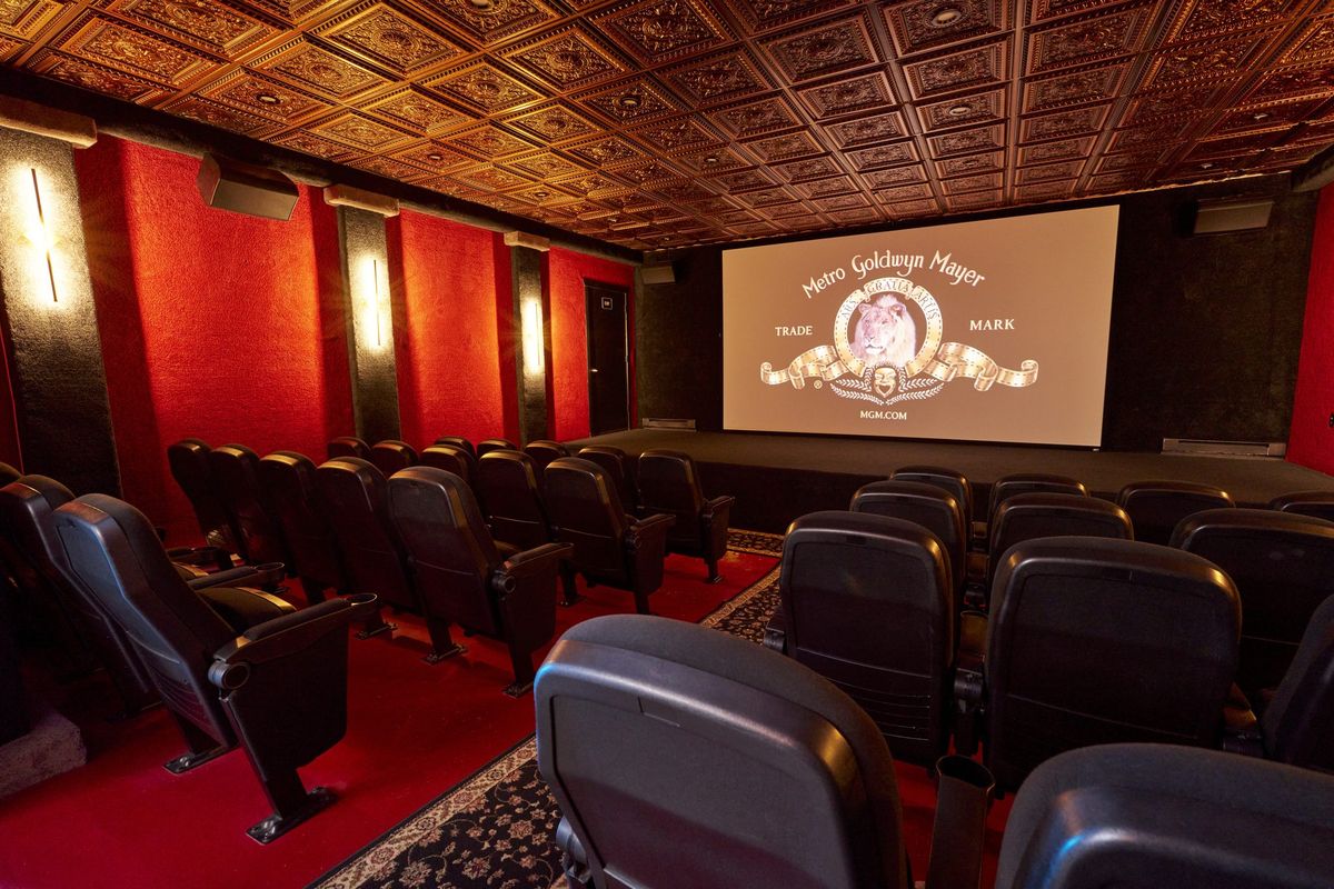 The Mansion's theater, red walls and a pressed tin ceiling above rows of recliners facing a screen