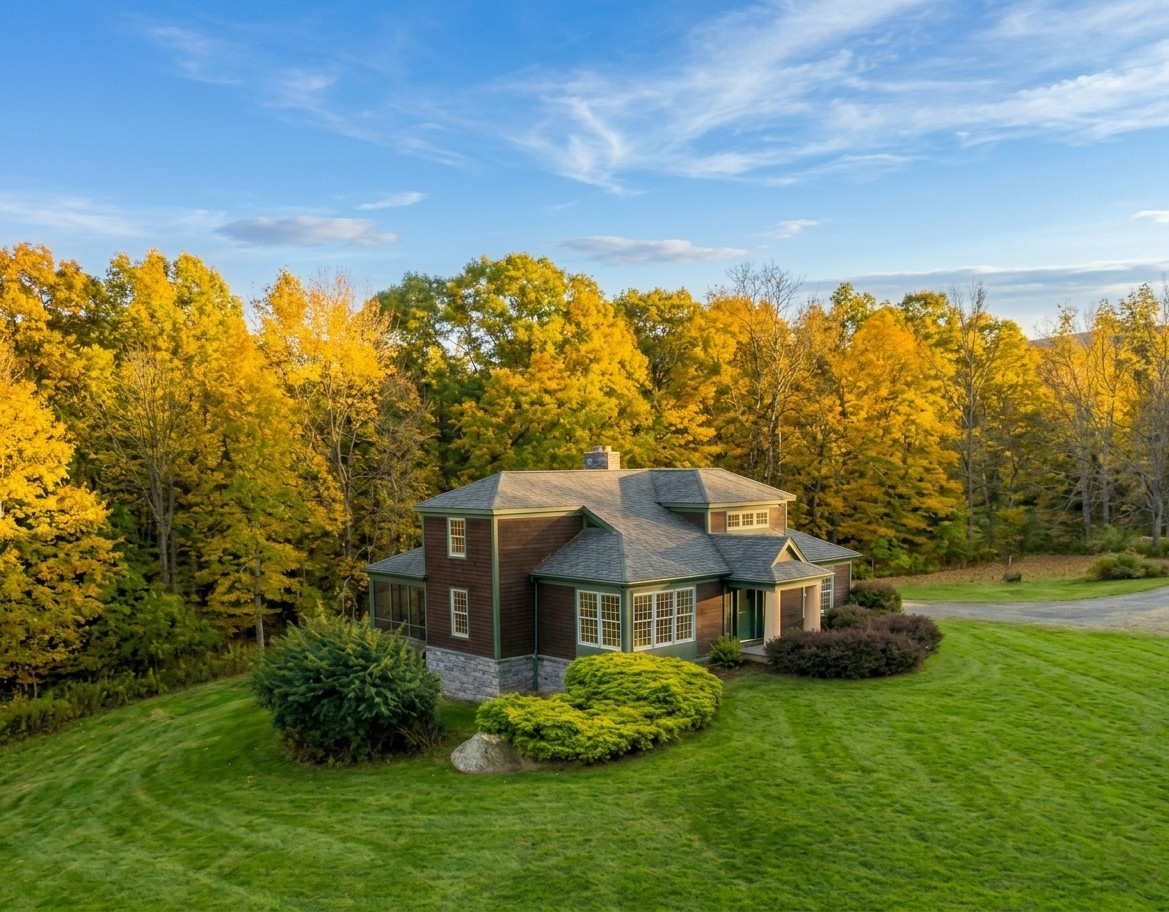 The Lodge from above in autumn, a striped lawn around it and yellow maples behind