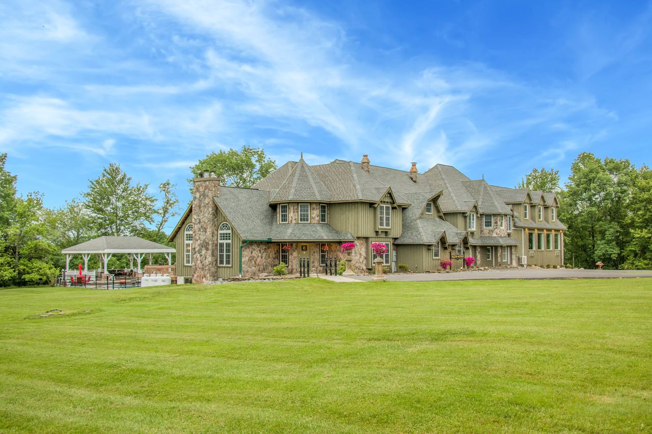 The Mansion from the lawn: a long stone and timber house with steep slate gables, a gazebo at the left